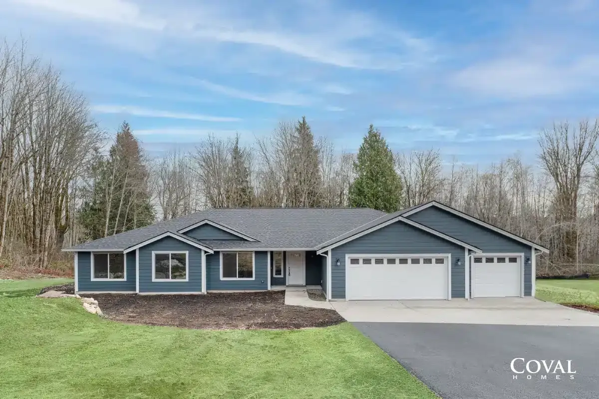 Blue single-story house with a three-car garage, gray roof, and a front lawn under a cloudy sky