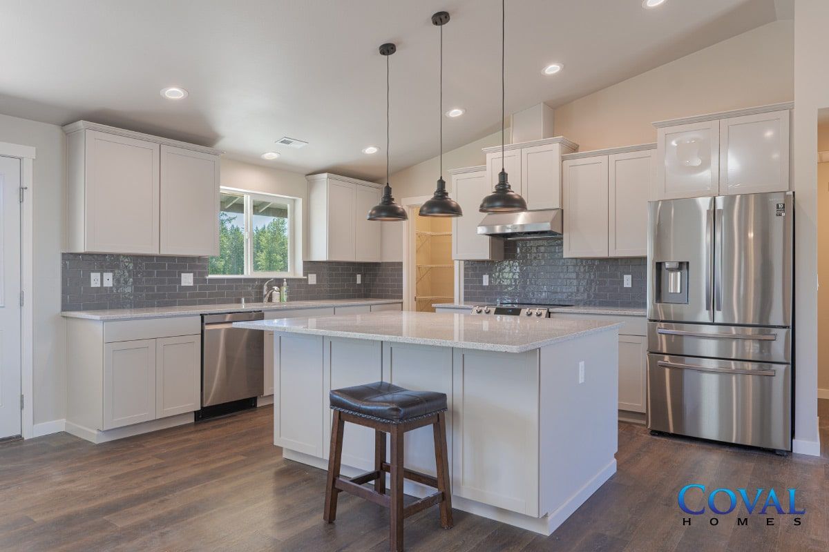 Bright modern kitchen with white cabinets, island, stainless steel appliances, and pendant lights.