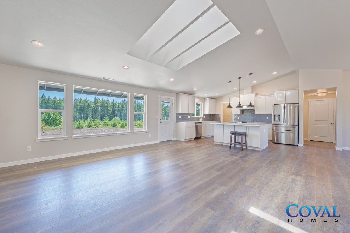 Bright open living room with skylights, large windows, wood floors, and a modern kitchen.