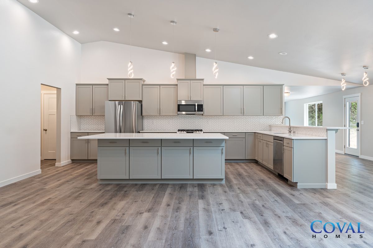 Bright modern kitchen with gray cabinets, stainless appliances, island, and wood-look flooring