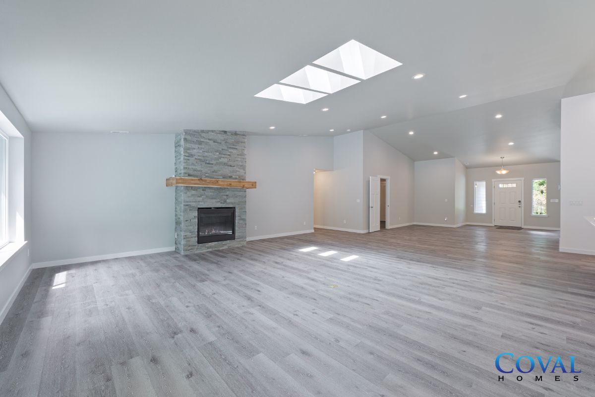 Bright open living room with gray wood floors, white walls, a fireplace, and skylights.