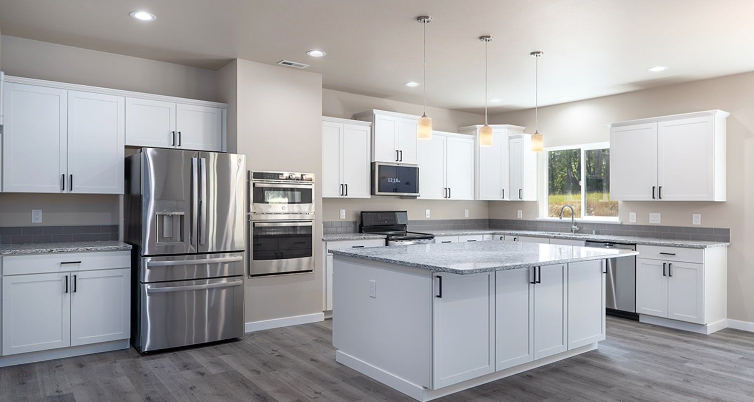 Modern white kitchen with stainless steel appliances, center island, and gray flooring