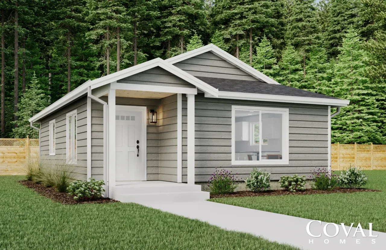 Modern gray single-story house with white trim, front porch, and green lawn in a wooded setting