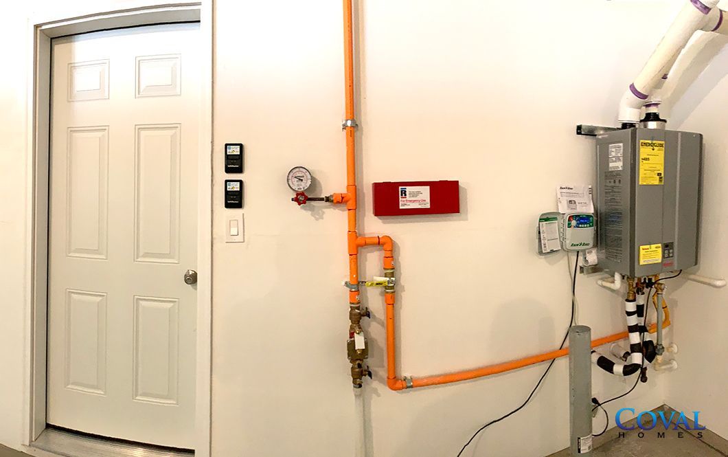 Utility room with white door, orange pipes, valves, and electrical panels on a wall