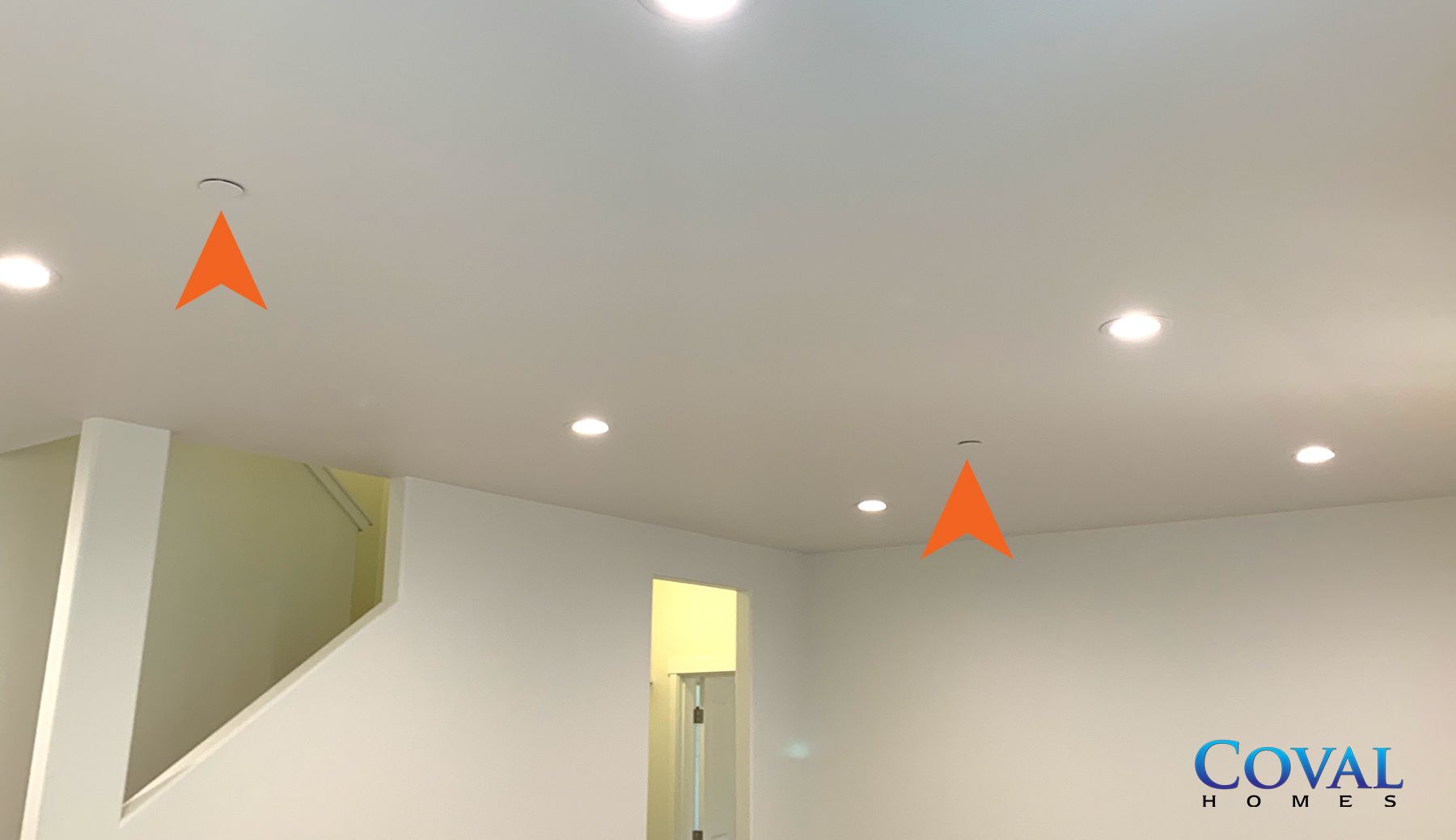 White ceiling with recessed lights in a room; orange arrows highlight two ceiling fixtures.