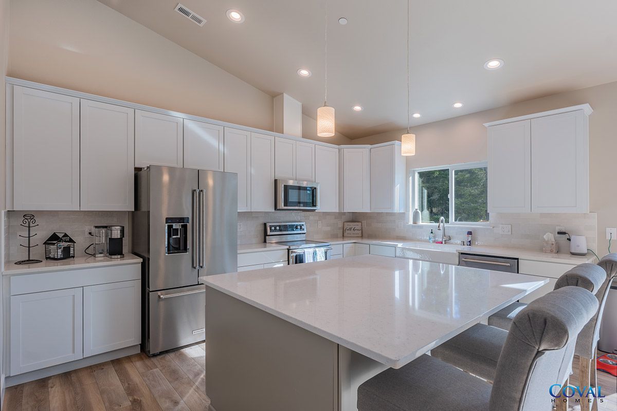 Bright modern kitchen with white cabinets, stainless steel appliances, island, and bar stools