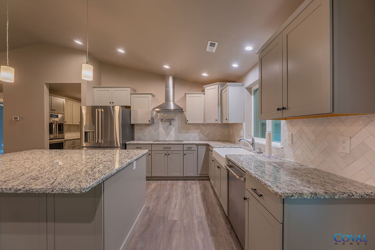 Modern kitchen with gray cabinets, granite island, stainless appliances, and wood-look flooring