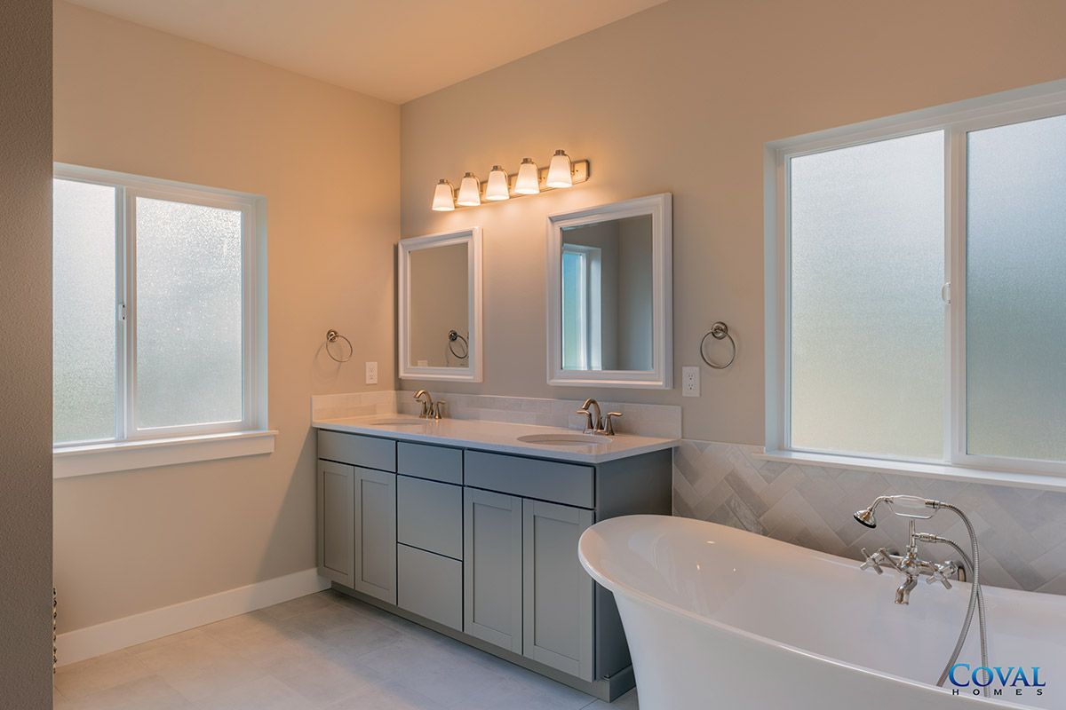 Bright modern bathroom with frosted windows, vanity mirror lights, and a bathtub.