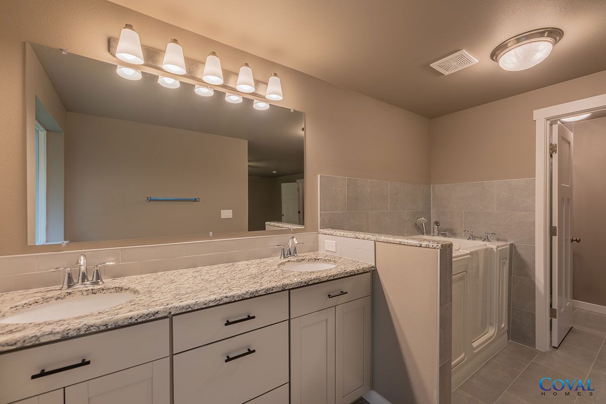 Spacious bathroom with double vanity, large mirror, granite countertop, and walk-in shower