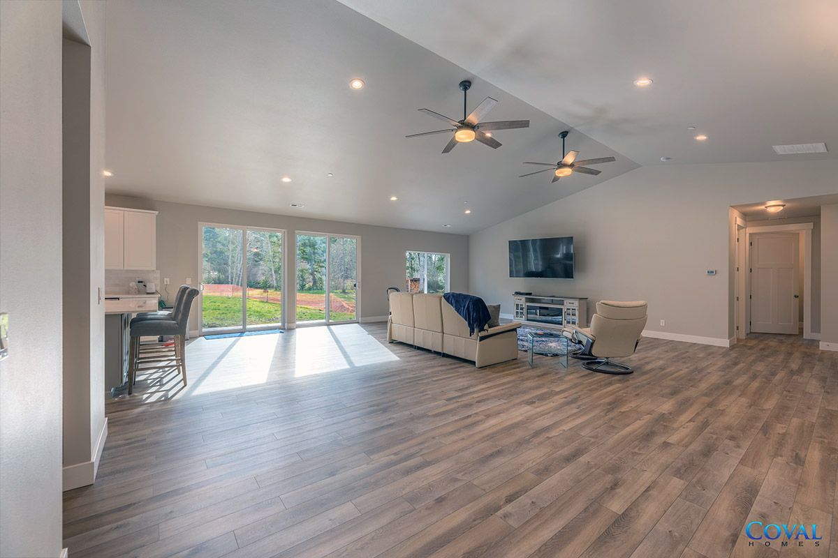 Spacious modern living room with sectional sofa, TV, ceiling fans, and sliding doors to a backyard.