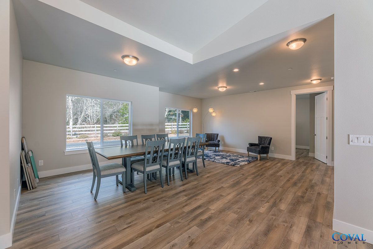 Spacious dining room with long table, chairs, wood floors, and large windows.