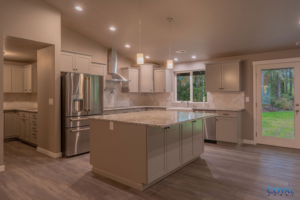 Modern kitchen with stainless appliances, large island, white cabinets, and windows overlooking a backyard