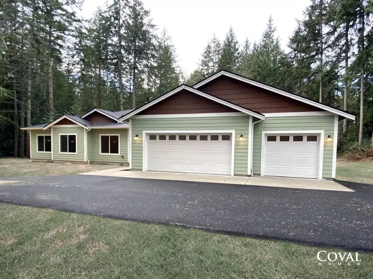 Single-story house with light green siding, brown trim, and three garages beside a paved driveway.