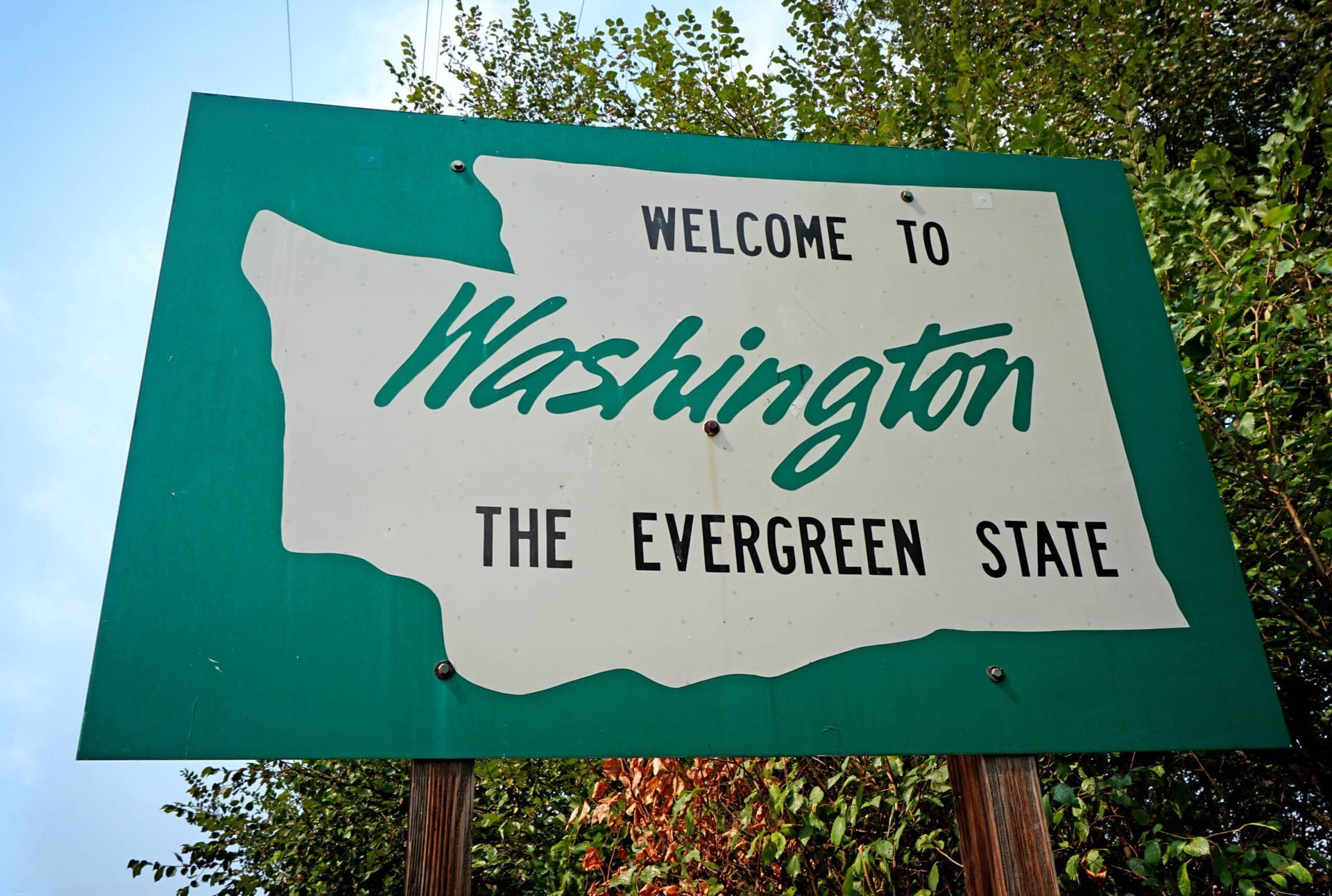 Welcome to Washington roadside sign on teal background, reading “The Evergreen State”