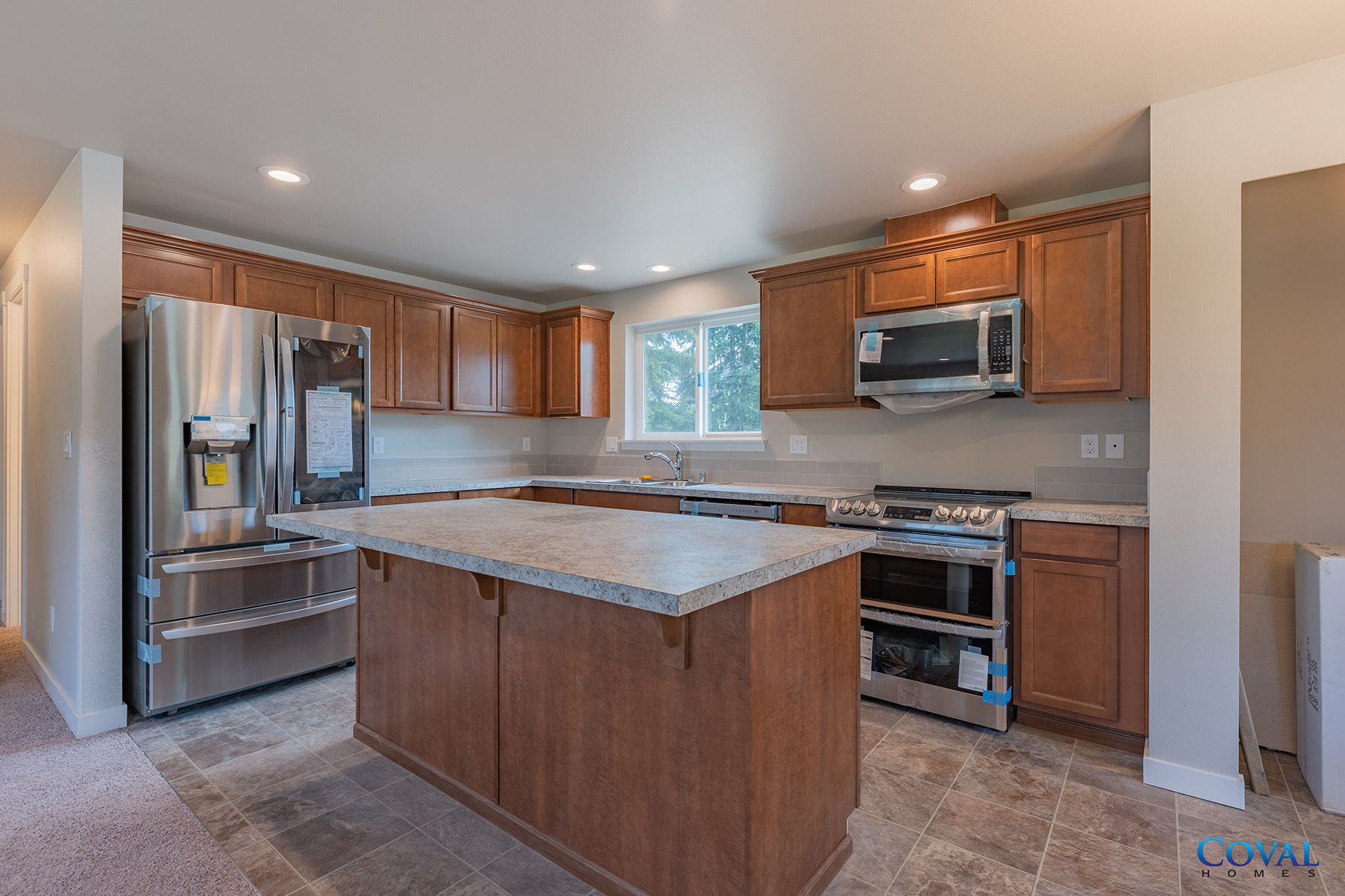 Modern kitchen with stainless steel appliances, wood cabinets, and a central island with granite countertop