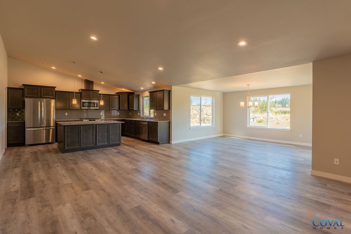 Spacious open-concept living room with modern kitchen, wood floors, and large windows.