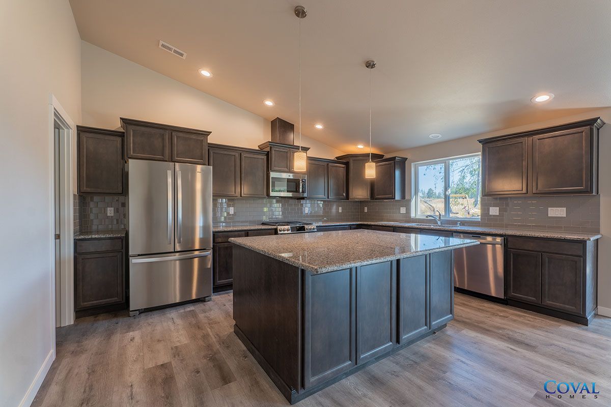 Modern kitchen with dark cabinets, stainless steel appliances, and a large granite island