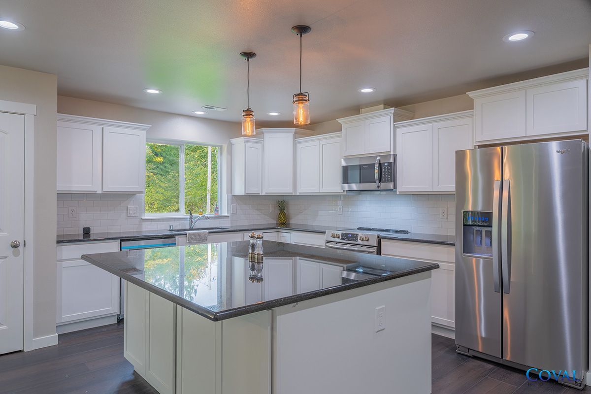 Bright modern kitchen with white cabinets, stainless appliances, and a large granite island