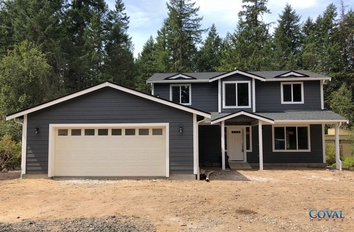 Dark gray two-story house with attached two-car garage in a wooded setting