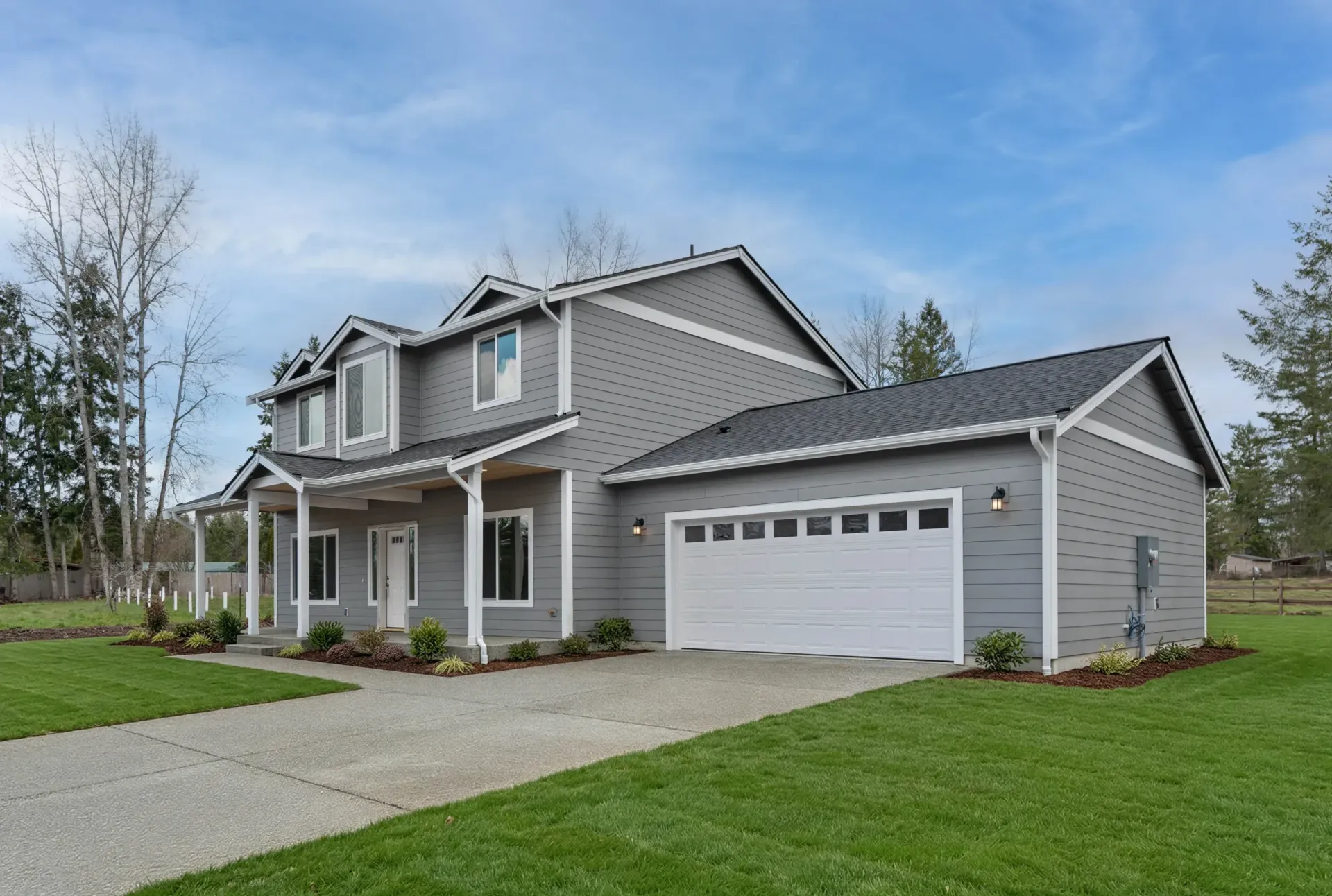 Gray two-story suburban house with attached garage and front porch on a green lawn