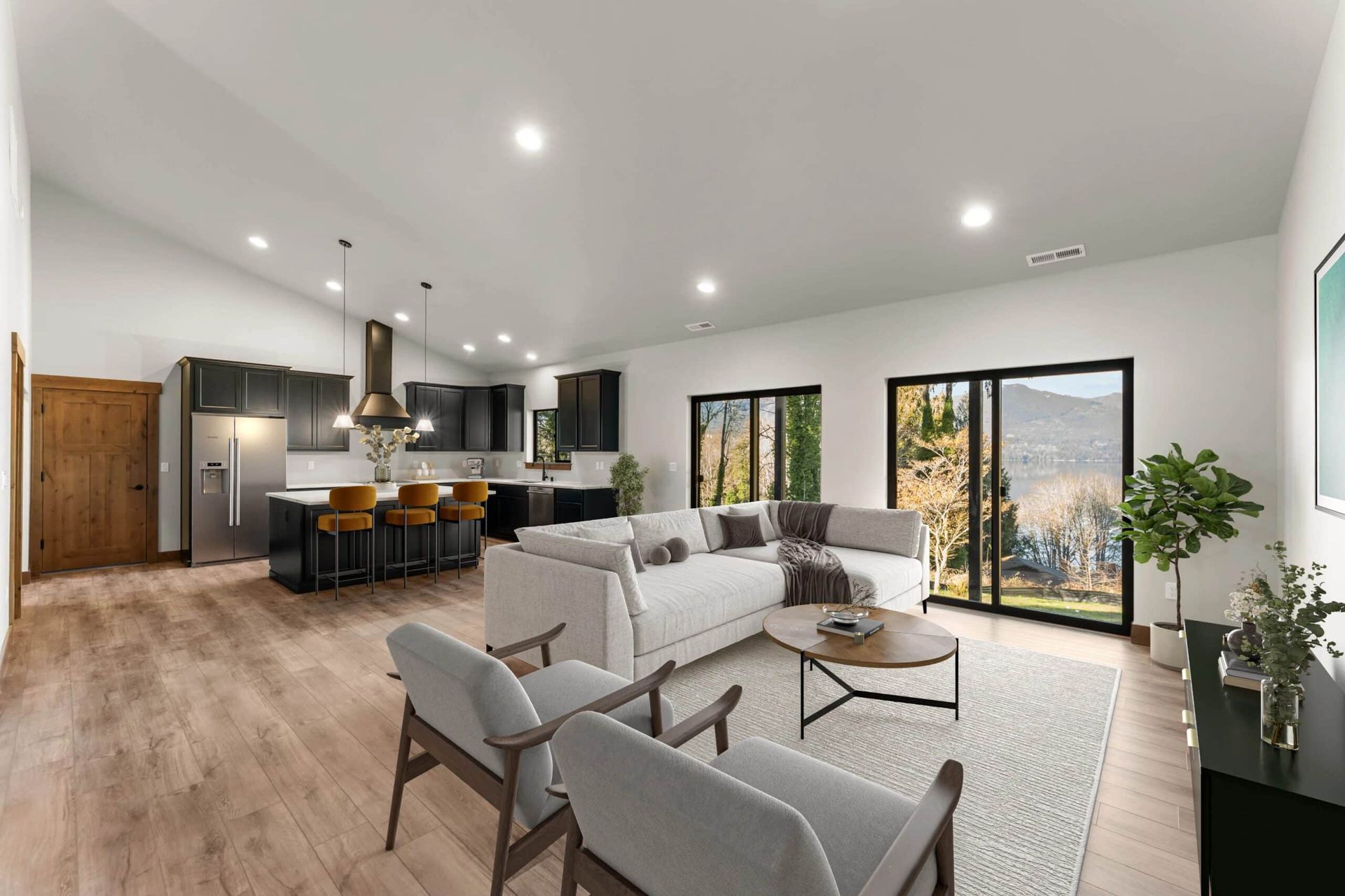 Modern open-plan living room with white sofa, gray chairs, kitchen island, and large sliding glass doors