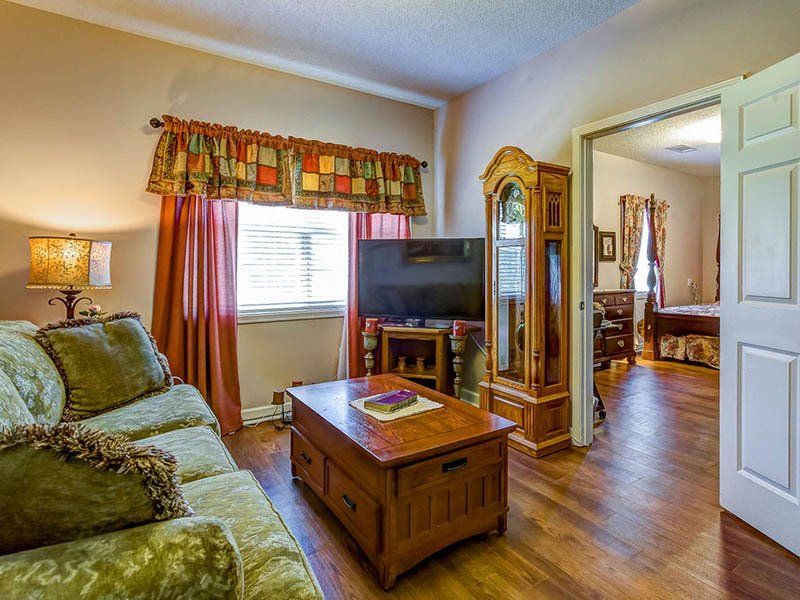 A living room with a couch , coffee table , television and grandfather clock.