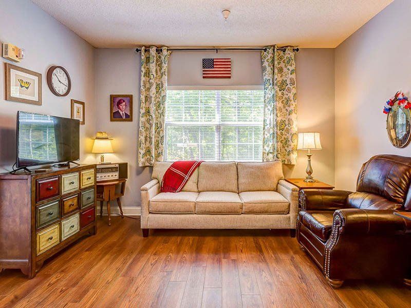 A living room with a couch , chair , television and dresser.