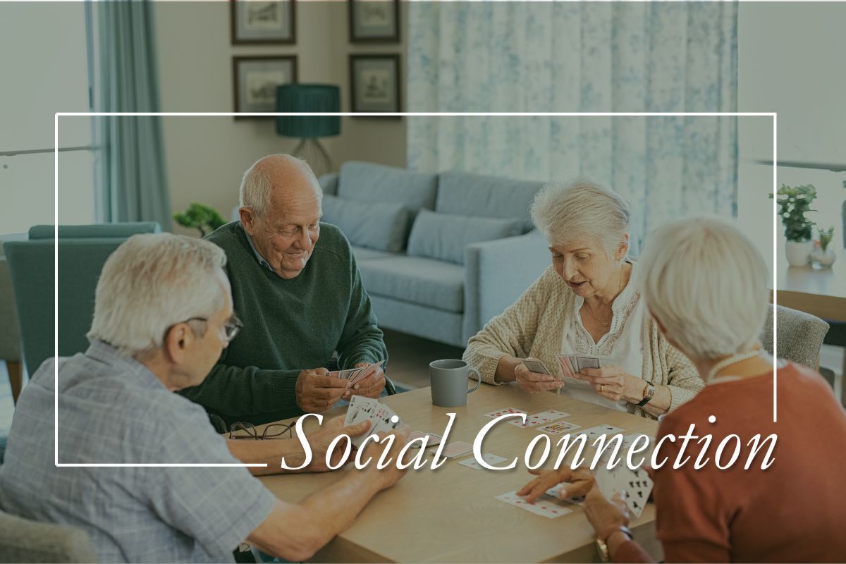 Four older adults playing cards at a table, promoting social connection.