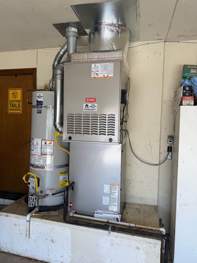 A light gray outdoor residential air conditioning unit sits on a concrete pad against a beige exterior wall.