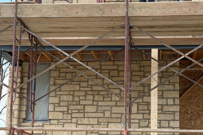 Stone wall facade with metal scaffolding in front of a building under construction