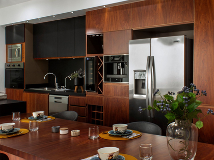 Modern kitchen and dining area with wood cabinets, stainless fridge, dark countertops, and set table