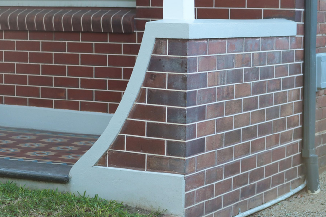 Brick house corner with a concrete ramp leading to the porch entrance