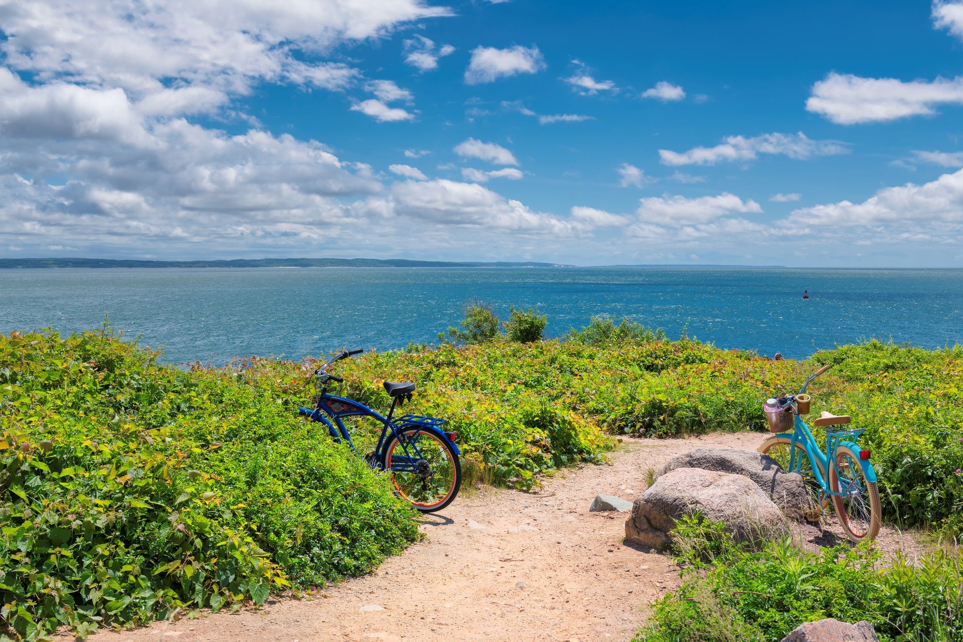 A blue bicycle is parked on a dirt path next to the ocean.