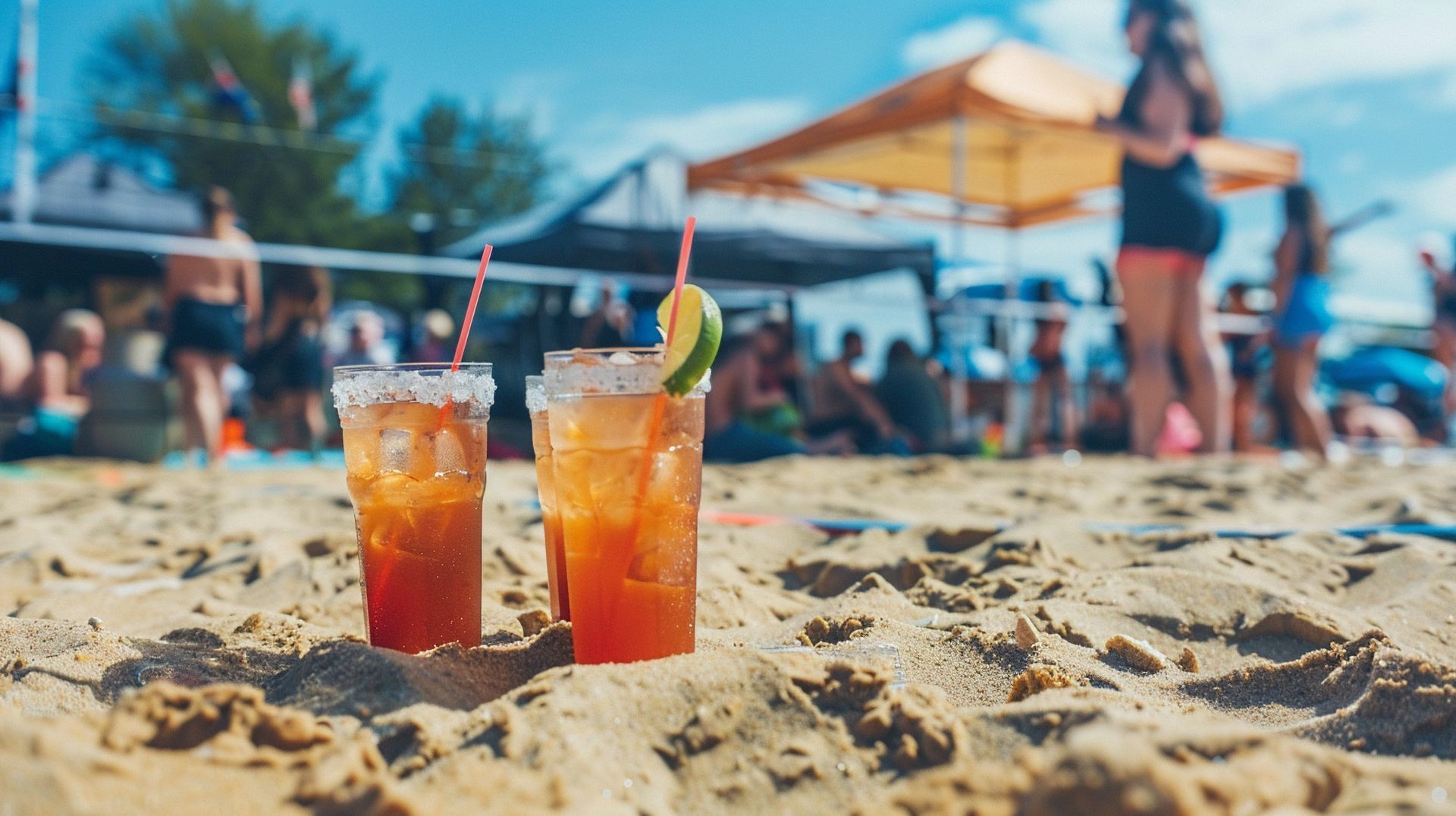 Two drinks are sitting on a sandy beach.
