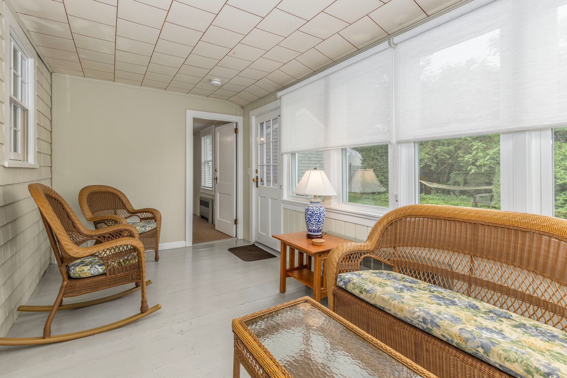 A living room with wicker furniture , rocking chairs , a couch and a table.