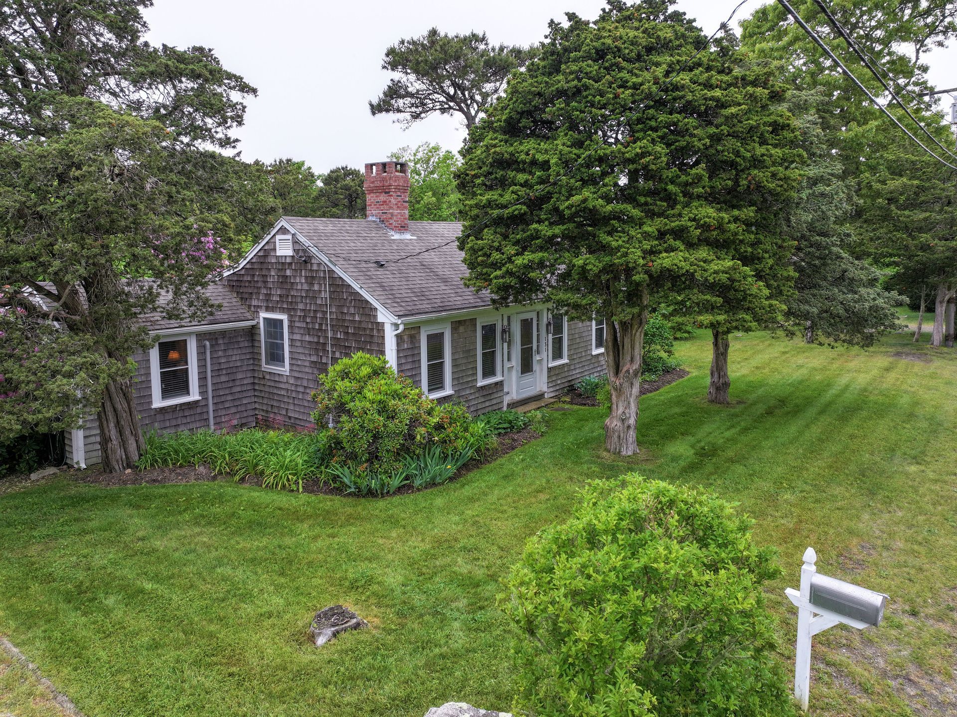 An aerial view of a house surrounded by trees and grass.