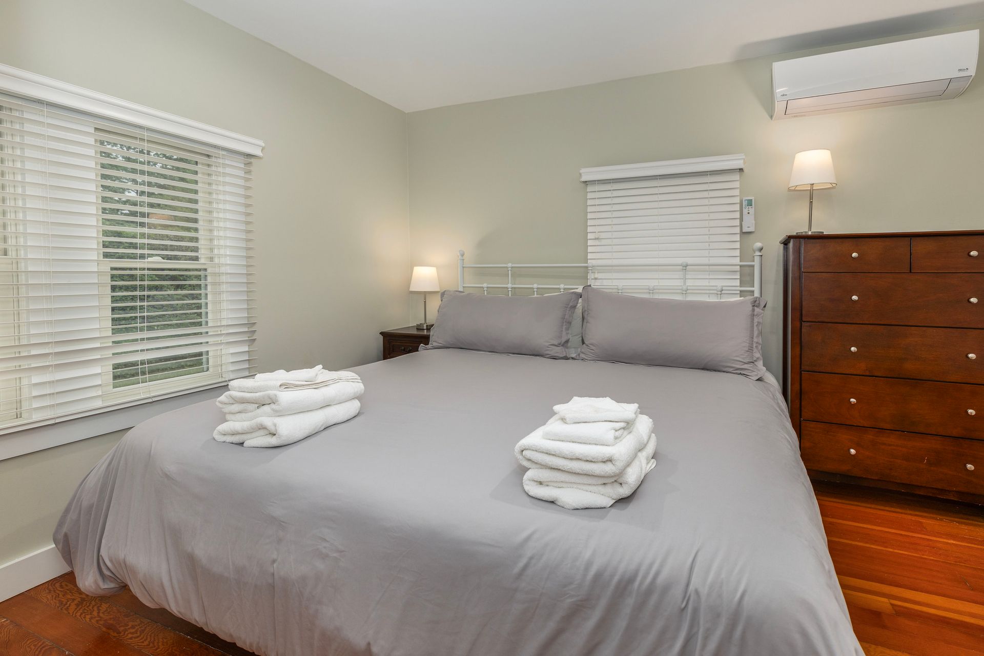 A bedroom with a bed , nightstand , lamps and a window.