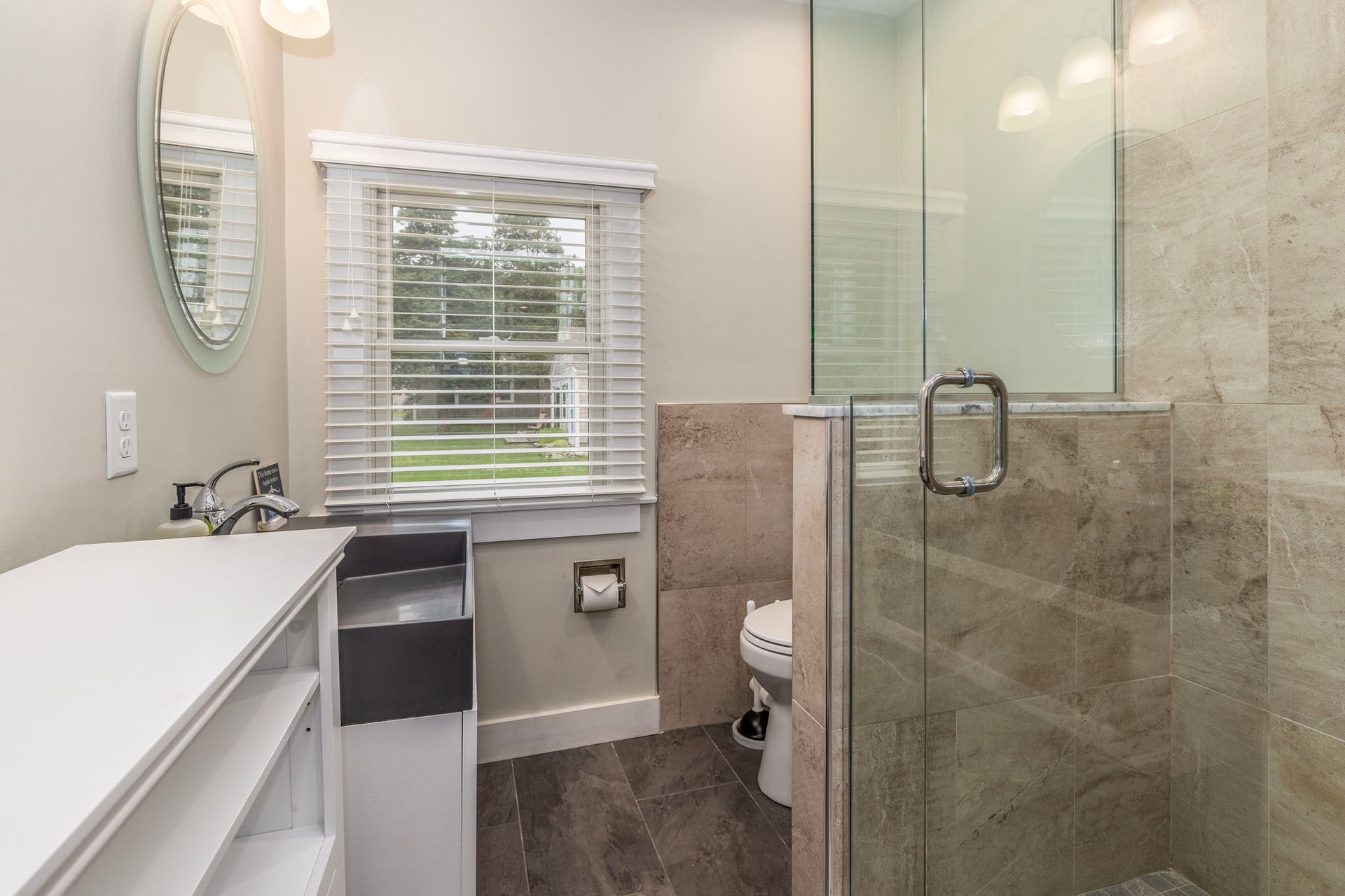 A bathroom with a walk in shower , sink , mirror and window.