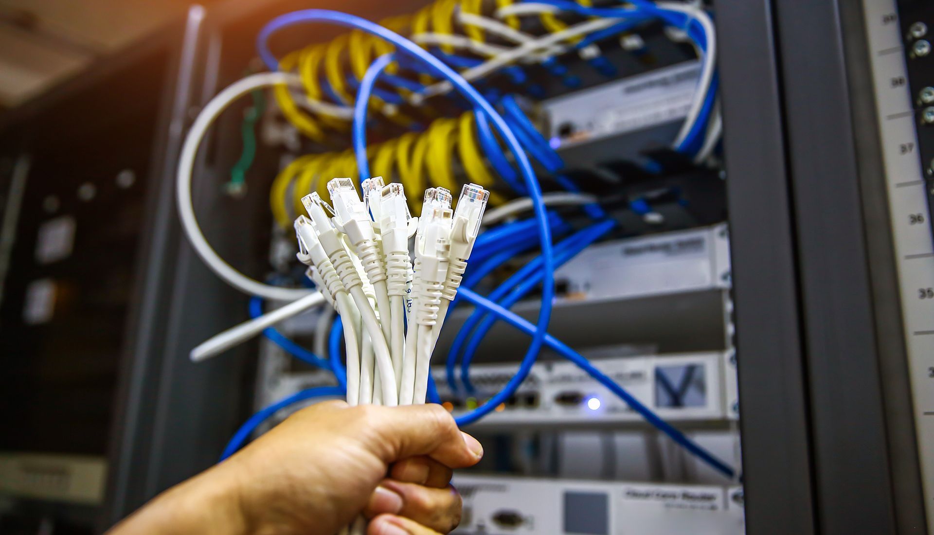 Server rack with orange fiber optic cables lit up.