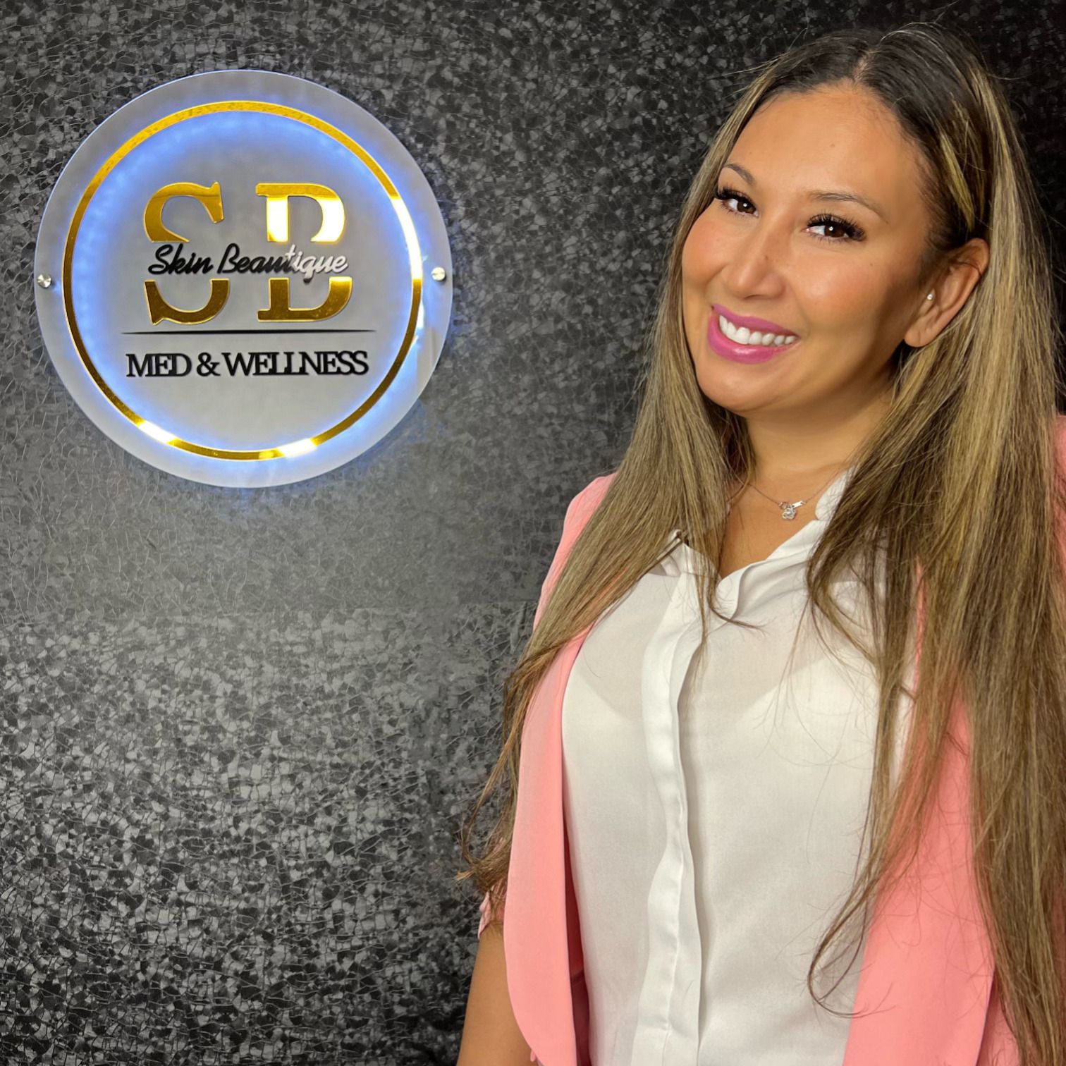 A woman is standing in front of a sign that says sb med & wellness