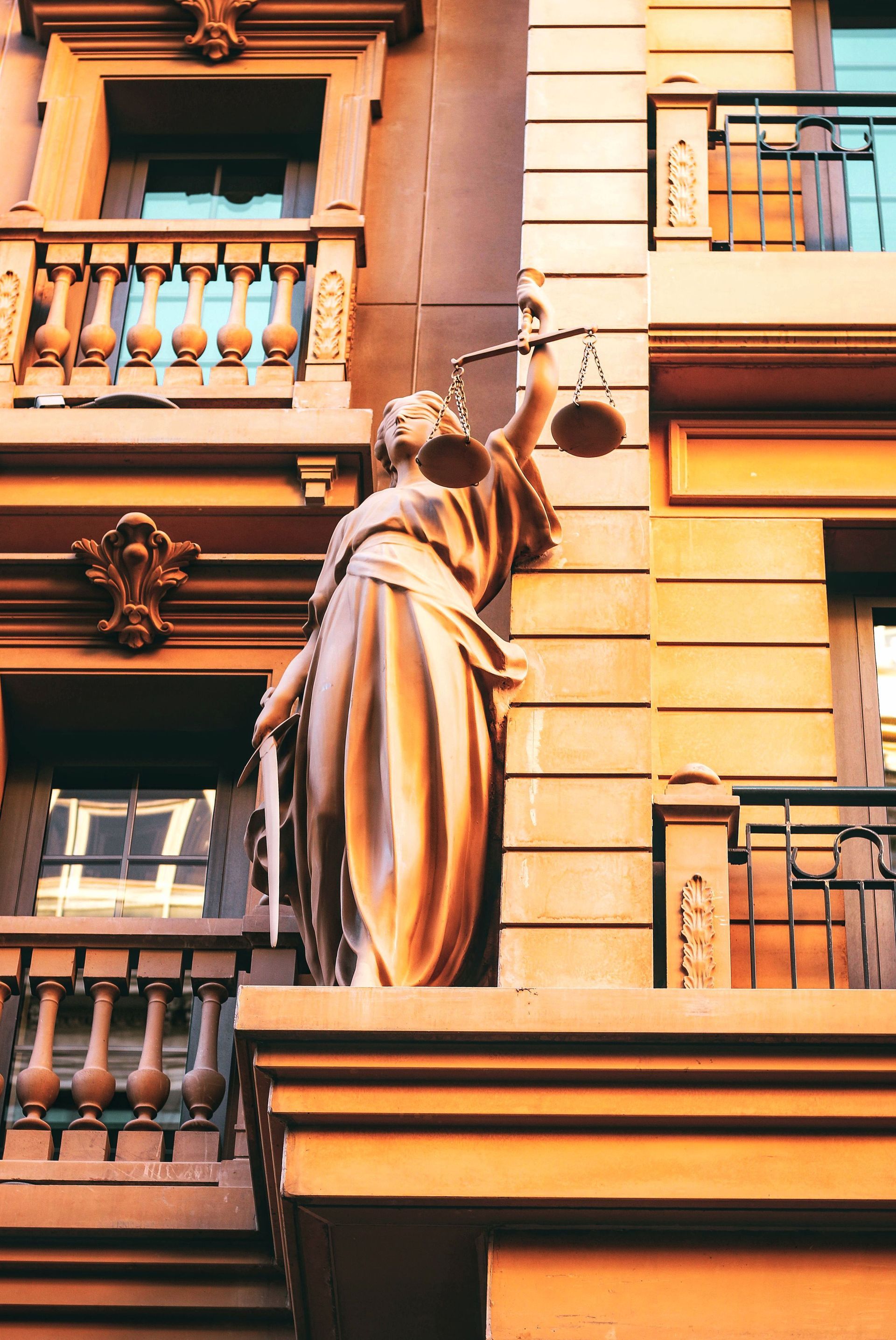 Bronze statue on a building facade with balconies and windows in warm sunlight