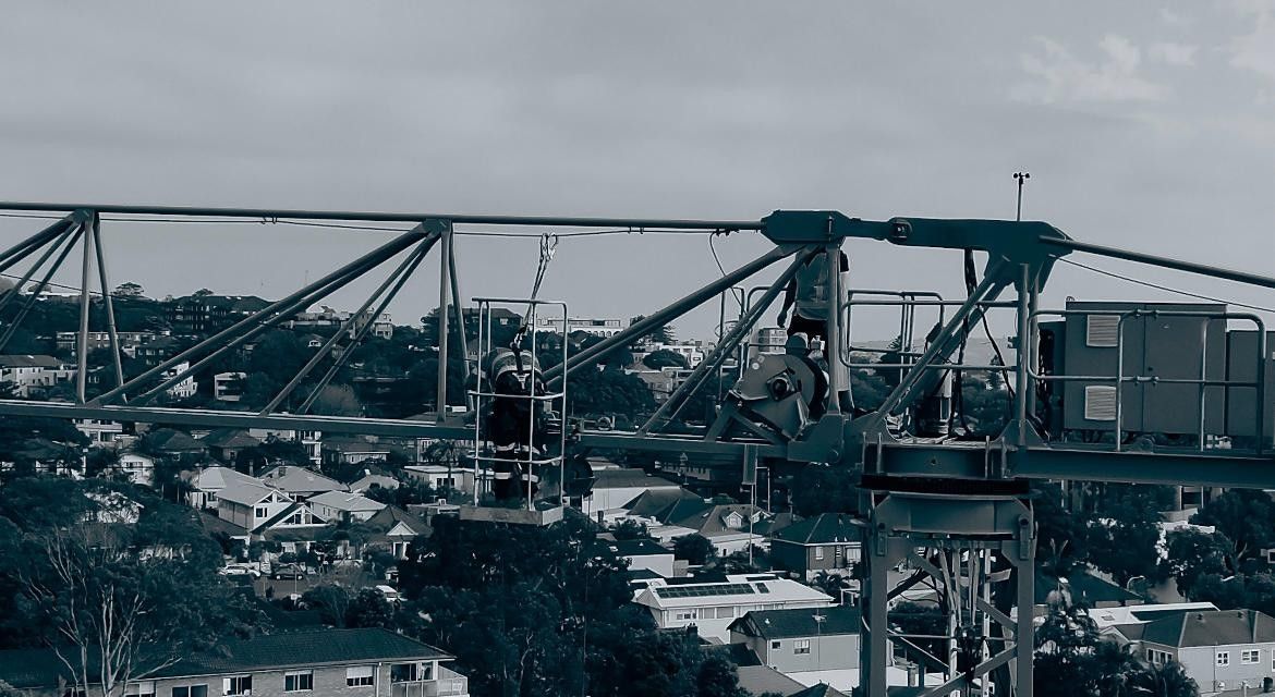 Tall yellow crane at a construction site beside unfinished concrete buildings under cloudy sky