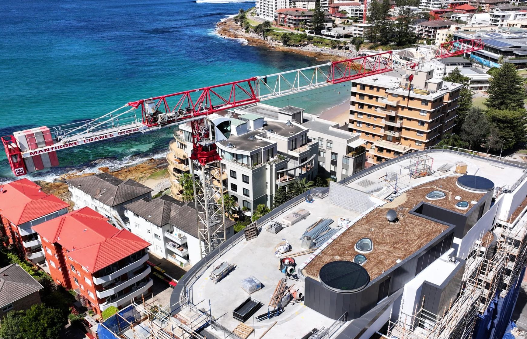 Tall construction crane above a partially built high-rise with city buildings in the background