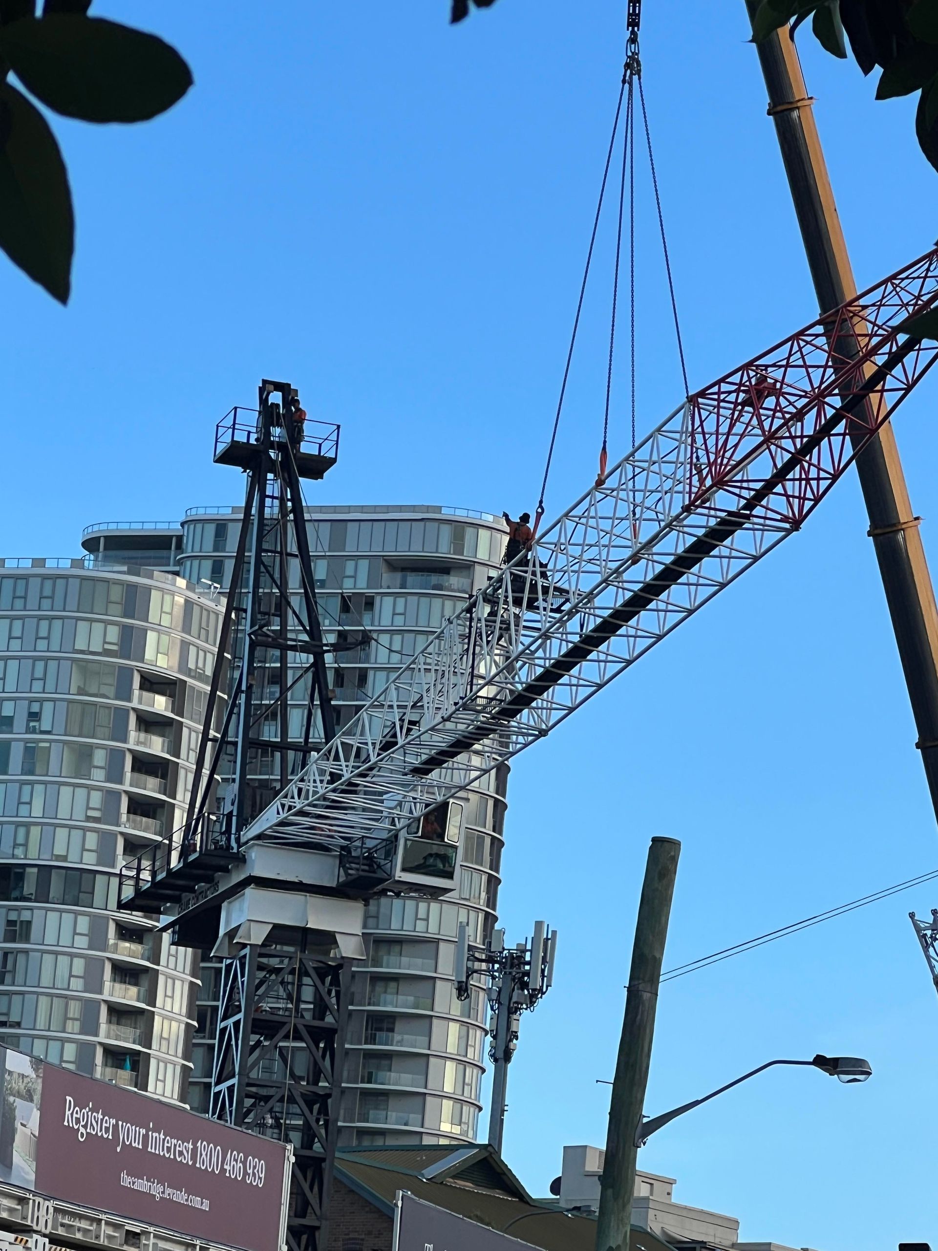 Tower crane mast and jib being assembled beside a multi-storey building