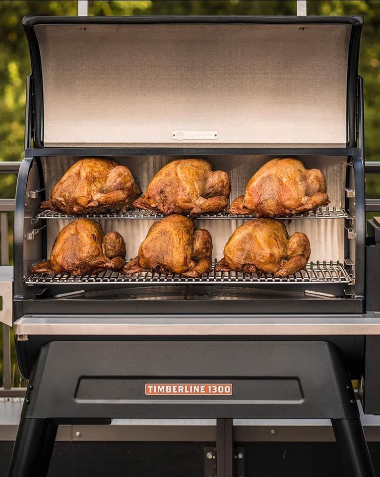 Six roasted turkeys inside a black and stainless steel smoker labeled 