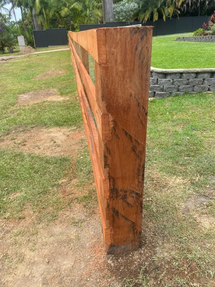 a Wooden Fence is Sitting in the Middle of a Lush Green Field — Tony Sinclair Fencing In Bellingen, NSW 
