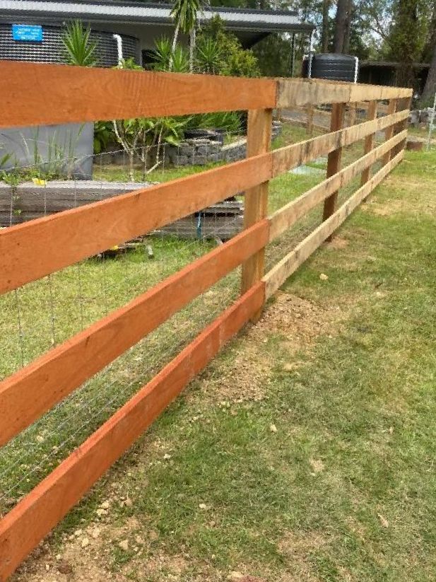 a Wooden Fence is Sitting in the Middle of a Lush Green Field — Tony Sinclair Fencing In Bucca, NSW