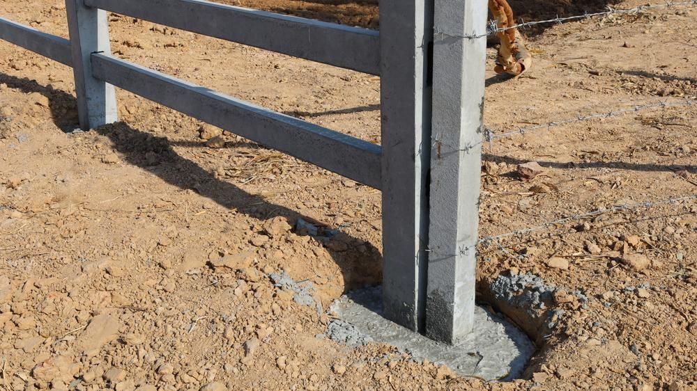 a Fence Post is Sitting in the Middle of a Dirt Field — Tony Sinclair Fencing In Dorrigo, NSW