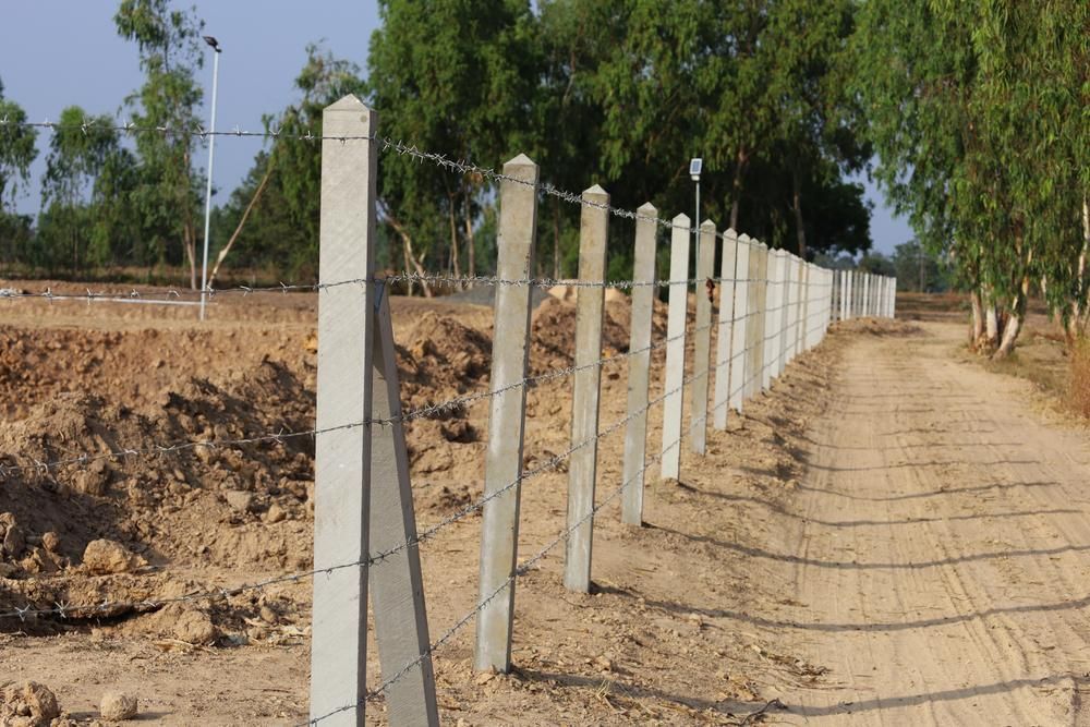 a Barbed Wire Fence is Along the Side of a Dirt Road — Tony Sinclair Fencing In Grafton, NSW