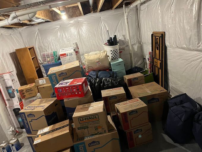 Two professional movers in matching uniforms carefully transport cardboard boxes through a modern and stylish apartment.